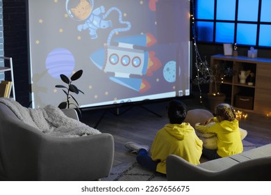 Little boy and his sister in 3D glasses watching cartoons on projector screen at home