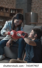 Little boy and his young mother fistbumping while wearing boxing gloves