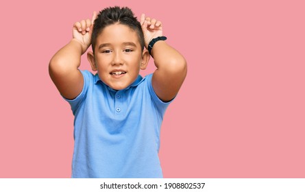 Little Boy Hispanic Kid Wearing Casual Clothes Doing Funny Gesture With Finger Over Head As Bull Horns 