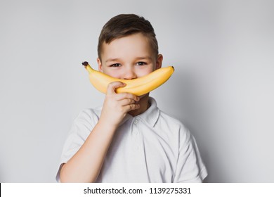 A Little Boy Is Holding A Banana Near His Face. Smile.