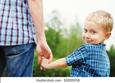 Little boy holding the hand of his father
