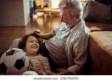 Little boy holding soccer ball bonding with grandfather at home - Powered by Shutterstock