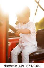 Little Boy Holding A Tractor Steering Wheel At Sunset