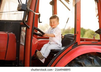 Little Boy Holding A Tractor Steering Wheel At Sunset