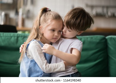 Little Boy Hugging Consoling Upset Girl Sitting On Sofa, Kid Brother Embracing Sad Sister Apologizing Or Comforting, Siblings Friendship, Preschool Children Good Relationships And Support Concept