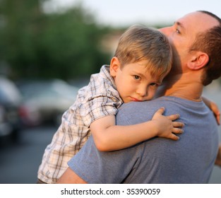 Little boy hugging hugging father around shoulders