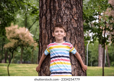 Little boy hugs a tree trunk - children love the nature, sustainability concept. Save the nature. - Powered by Shutterstock