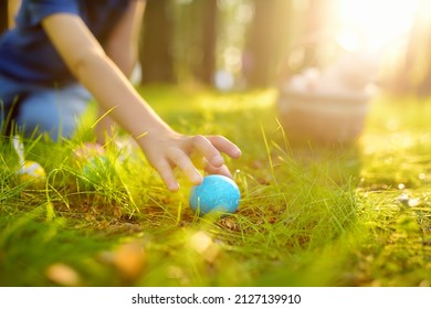 Little boy hunting for egg in spring garden on Easter day. Traditional festival outdoors. Child celebrate Easter holiday. Focus on multicolor eggs. - Powered by Shutterstock