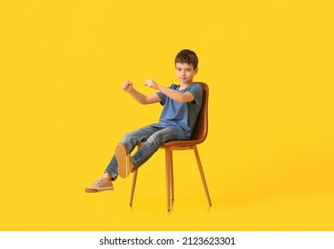 Little Boy With Imaginary Steering Wheel Sitting In Chair On Color Background