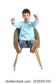 Little Boy With Imaginary Steering Wheel Sitting In Chair On White Background