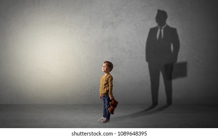 Little boy imagine that he will be businessman and illustrating his future in a big shadow