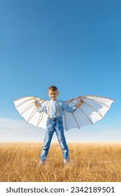 Little boy imagines flying.
Cheerful and happy child plays and dreams about airplanes with wings in the field against the blue sky. - Shutterstock ID 2342189501