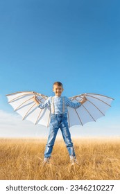 Little boy imagines flying.
Cheerful and happy child plays and dreams about airplanes with wings in the field against the blue sky. - Shutterstock ID 2346210227