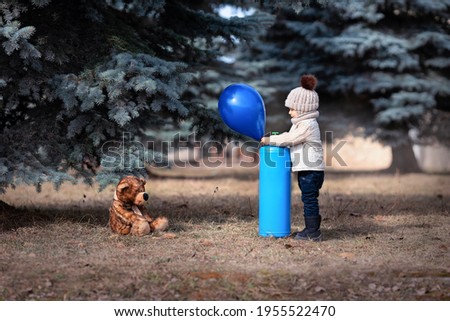 A little boy inflates a balloon with helium. Baby and his friend bear in the park. Winnie the Pooh. Spring walk of a child with a toy. Childhood. Based on a fairy tale. helium tank
