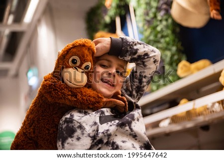 A little boy keeps a monkey toy in the store
