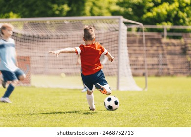 Little Boy Kick Soccer Ball During League Match. Happy Kid Have Fun Shooting Ball Towards Soccer Goal. School Soccer Tournament Game For Kids - Powered by Shutterstock