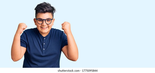 Kleiner Junge Kind mit lockeren Kleidung und Brille feiern überrascht und erstaunt für Erfolg mit Armen erhöht und offene Augen. Gewinnerkonzept. 