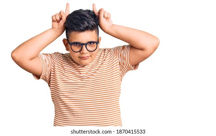 Little Boy Kid Wearing Casual Clothes And Glasses Doing Funny Gesture With Finger Over Head As Bull Horns 