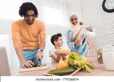 A Little Boy In The Kitchen With His Family. This Is An Arab Family. A Woman Is Wearing A Hijab. They Cook Together. Family Cooking Concept.