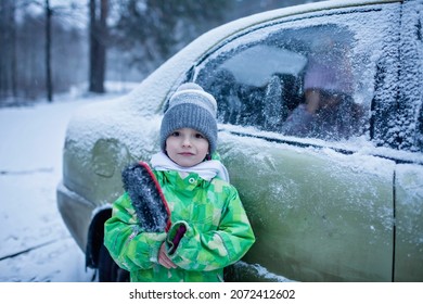 Little Boy In Knitted Hat Holding A Brush For Snow Removing From Vehicle Surface During Winter Road Trip With The Whole Family, Active Weekend In Any Weather, Winter Car Safety