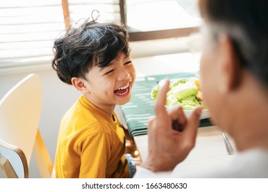 Little Boy Laughing While His Grandpa Tell Him The Funny Story During Breakfast.