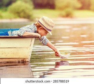 Little Boy Launch Paper Ship From Old Boat On The Lake