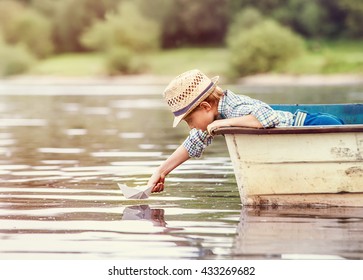 Little Boy Launch Paper Ship From Old Boat On The Lake