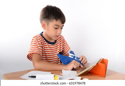 Little Boy Learning How To Fold A Piece Of Paper By Watching Tablet How To Do