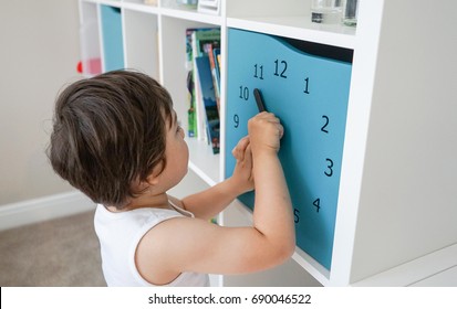 A little boy learning time with clock toy in his bed room,Kid learning to tell time, Concept of learning by playing for toddler development                               