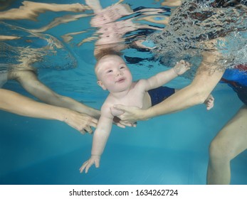 Little Boy Learns To Dive Underwater In A Swimming Pool, Mother And Teacher Holding The Child. 
