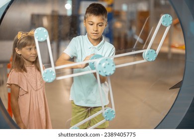 Little boy learns physics interactively on a model that shows physical phenomena while visiting a science museum. Concept of children's entertainment and learning