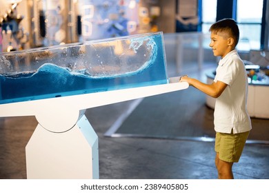 Little boy learns physics interactively on a model that shows physical phenomena while visiting a science museum. Concept of children's entertainment and learning
