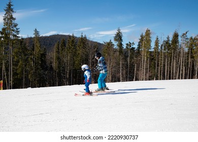 Little Boy Learns To Ski With His Father In Snowy Mountains During Winter Holidays On A Sunny Cold Day. Family Interesting Pastime, Healthy Lifestyle. Seasonal Joys, Happy Childhood. Frosty Weather