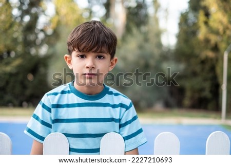 Little boy looking at camera behind the fences