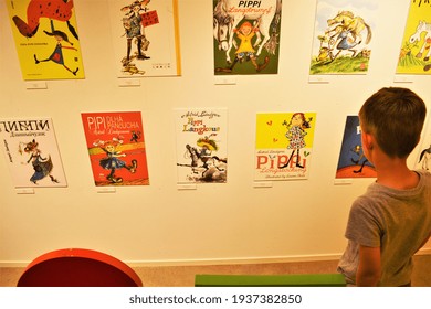 A little boy looking at different multilingual book covers of Pippi Longstocking books at Astrid Lindgren's World theme park, Vimmerby, Sweden. 