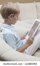 Little boy looking at digital tablet while sitting on sofa