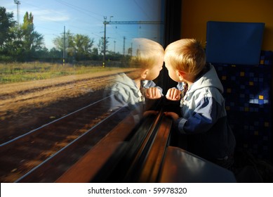 Little boy looking through window. He travels on a train.