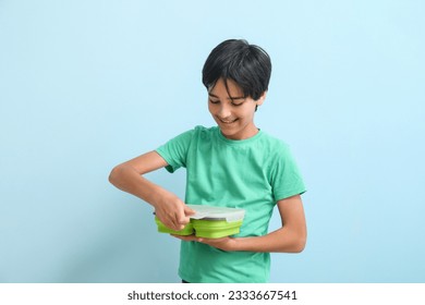 Little boy with lunchbox on blue background - Powered by Shutterstock