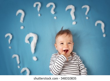 little boy lying on blue blanket with lots of question marks - Powered by Shutterstock