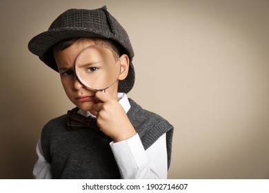Little boy with magnifying glass playing detective on beige background. Space for text