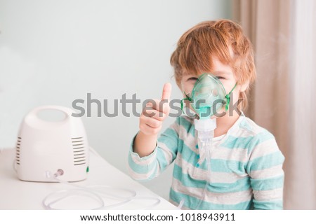 Little boy making inhalation with nebulizer at home. 
