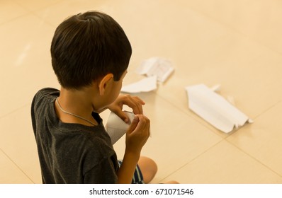 Little Boy Making Paper Plane At Home