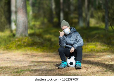 Little Boy With A Mask And Soccer Ball In The Park. Corona Virus Quarantine