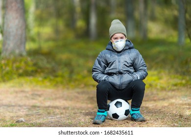 Little Boy With A Mask And Soccer Ball In The Park. Corona Virus Quarantine