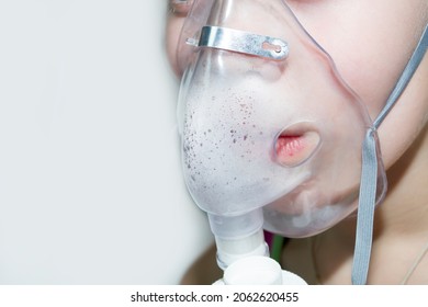 Little boy in a mask, treatments respiratory tract with a nebulizer at home. Baby sits with a nebulizer in his mouth, inhaler, treatment of bronchitis. Nebulizer, cute boy using inhaler.