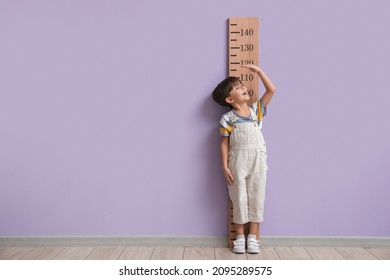 Little Boy Measuring Height Near Color Wall