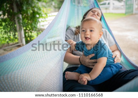 Der kleine Junge und die Mutter sitzen an der Hängematte.