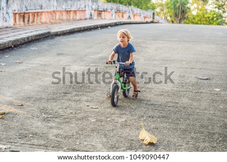 Little boy on a bicycle. Caught in motion, on a driveway motion blurred. Preschool child's first day on the bike. The joy of movement. Little athlete learns to keep balance while riding a bicycle