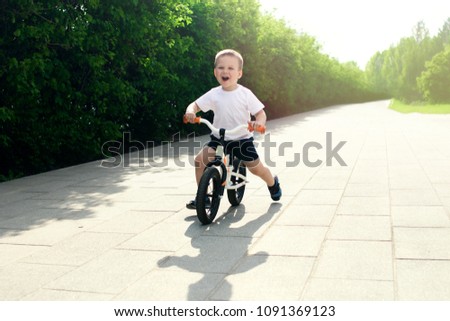 Little boy on a bicycle. Caught in motion, on a driveway. Preschool child's first day on the bike. The joy of movement. Little athlete learns to keep balance while riding a bicycle. 