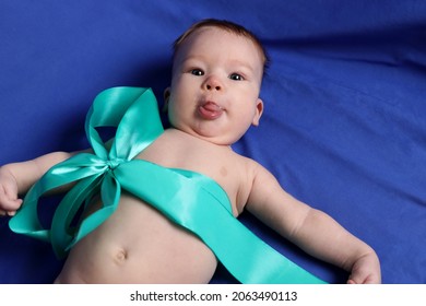 Little Boy On The Blue Bed Cover Puts Out Tongue